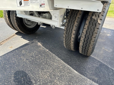 Trailer undercarriage with dual rear tires showing wheel rims and suspension, low ground clearance, concrete surface.