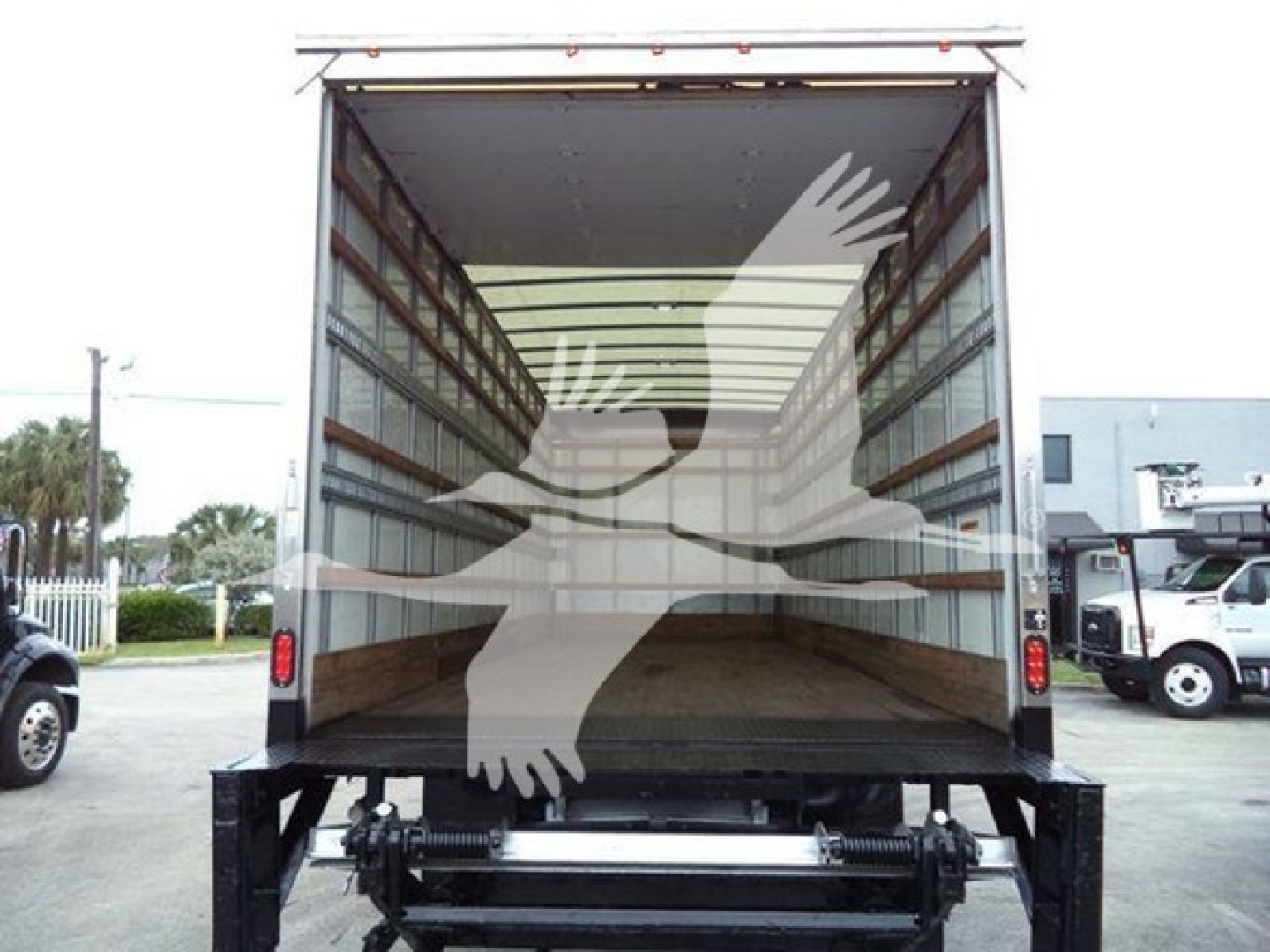 Interior of a box truck with empty cargo area, open rear doors, and metal loading frame visible.