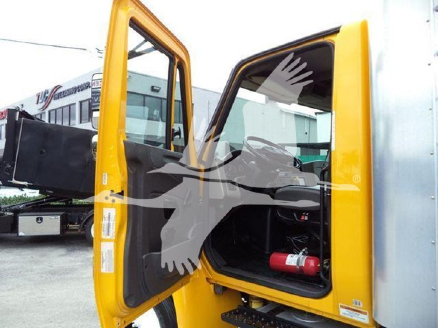 Truck cab interior with open doors showing yellow International Durastar 4300 and storage area, VIN 3HAMMMML4KL385260 in listing.