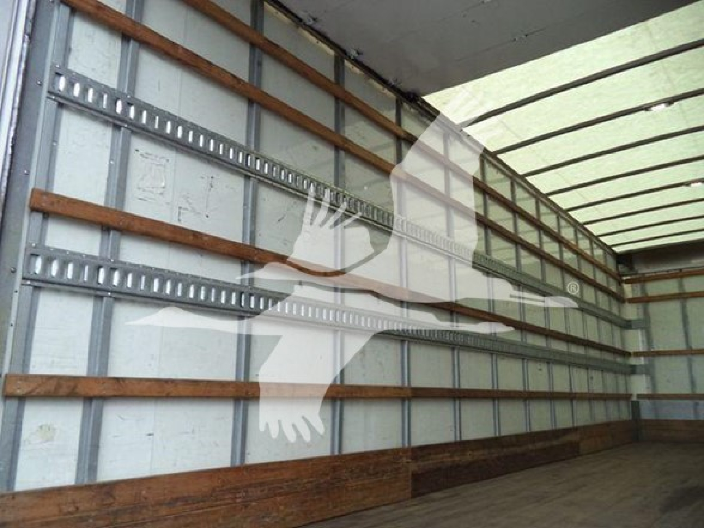 Interior of a cargo box truck showing wooden side slats and metal tracks along the walls.