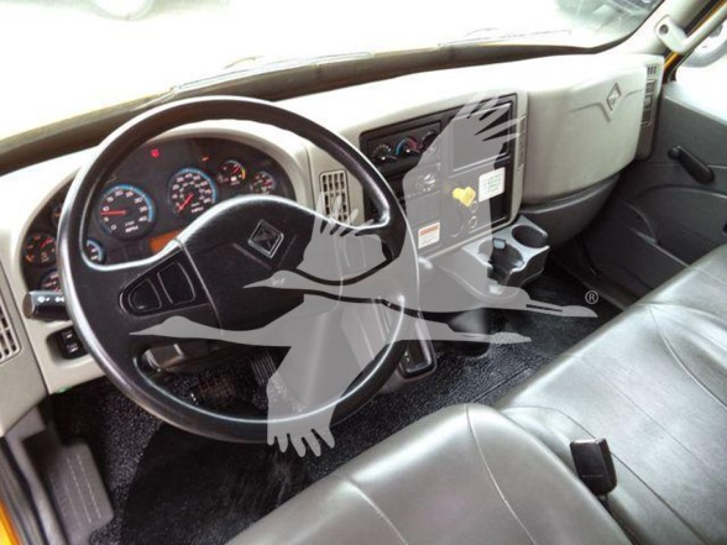 Truck cab interior of 2019 International Durastar 4300 showing steering wheel dashboard and driver seat with dashboard gauges and center console.