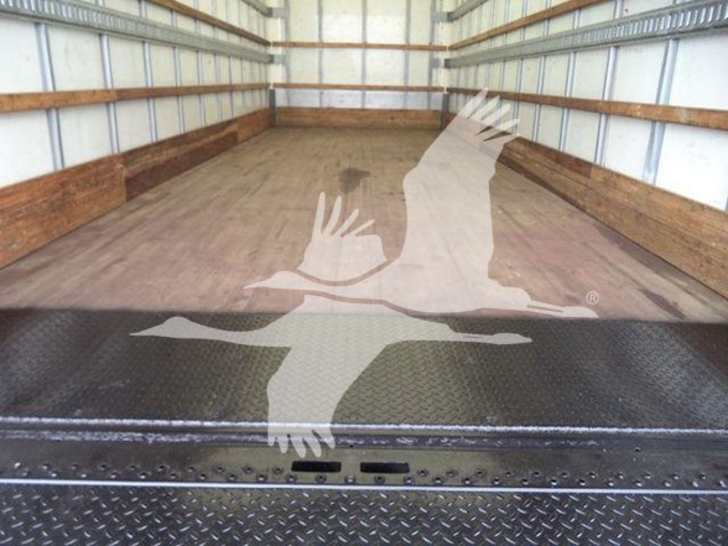 Truck bed of 2019 International Durastar 4300 showing empty box area and metal floor with diamond plate at rear.