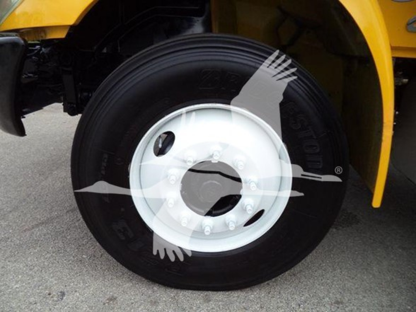 Truck wheel with white hub and black tire on a yellow International Durastar 4300; partial fender and body in background.