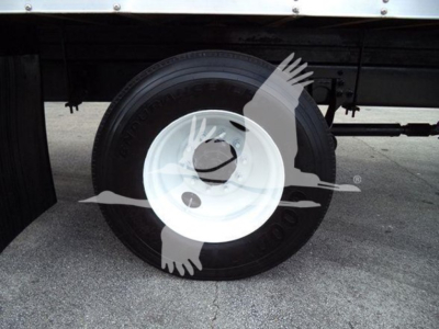 Truck wheel and white steel rim under a box truck; partial undercarriage visible.