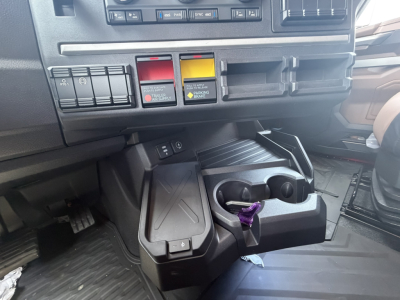 Mack PR64T76H truck dashboard area showing switch panel, colored indicators, and cup holders with key fob in the center console.