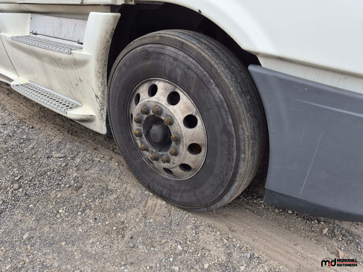 Freightliner Cascadia front wheel and fender with steel rim and hub, undercarriage and side step visible.