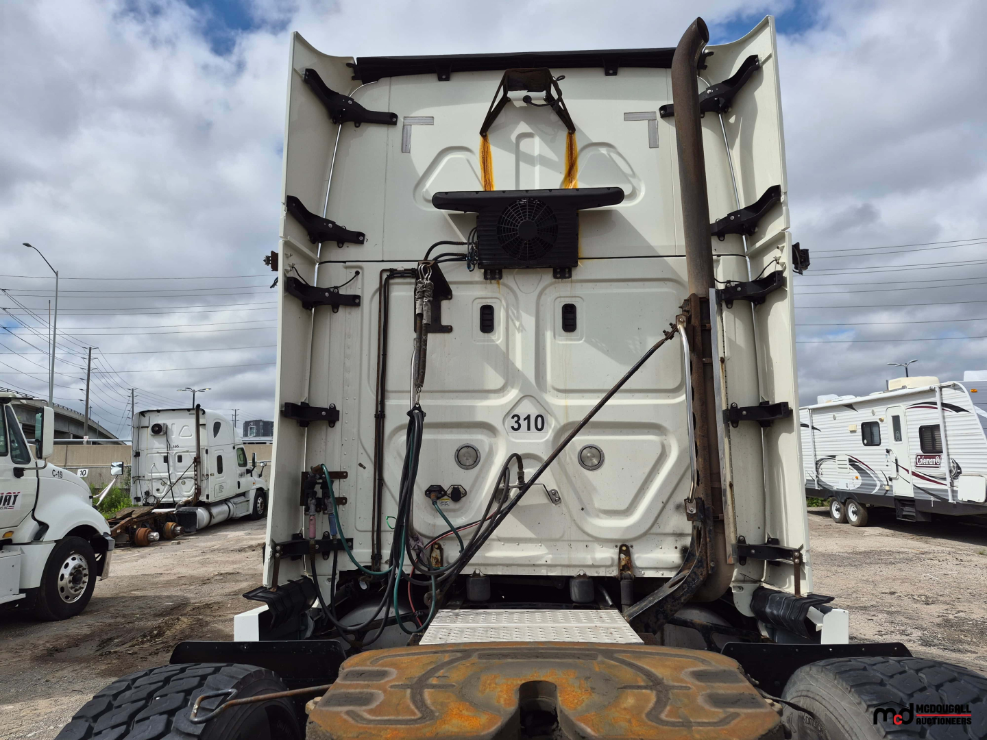 Rear view of a Freightliner Cascadia sleeper tractor showing back of cab, lifting system, hoses, and bumper with rear decals.