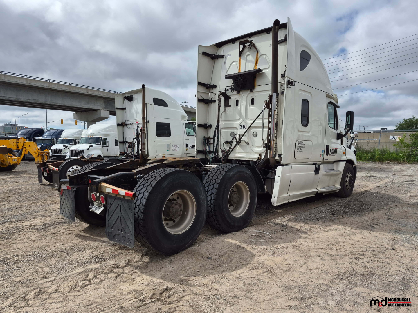 Freightliner Cascadia tractor rear view showing fifth wheel and dual rear axles with mud flaps and tires.