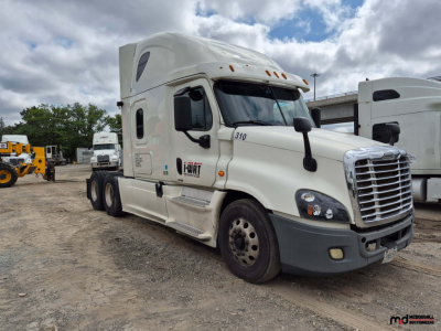 2017 Freightliner Cascadia conventional sleeper truck in a used lot, white cab with trailers in background, visible VIN and company branding on door