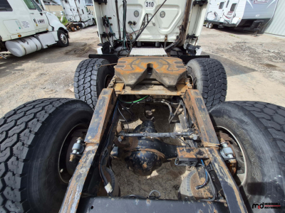 Freightliner Cascadia truck chassis rear view showing dual rear axles and fifth-wheel mounting with rust and wear
