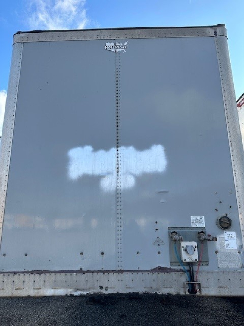 Rear view of a 2014 Wabash roll-door trailer showing a tall gray exterior with a vertical seam, door hardware, and a small utility box near the bottom right.