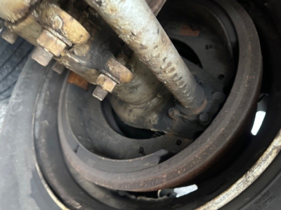 Rail wheel hub with hydraulic brake components and rusted spool showing a close-up of a trailer axle assembly.