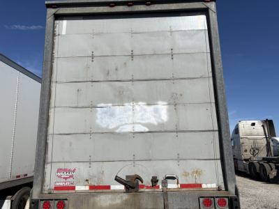 Rear of a 2014 Wabash roll door trailer showing the closed vertical roll-up door, bumper area with lights and reflective tape.