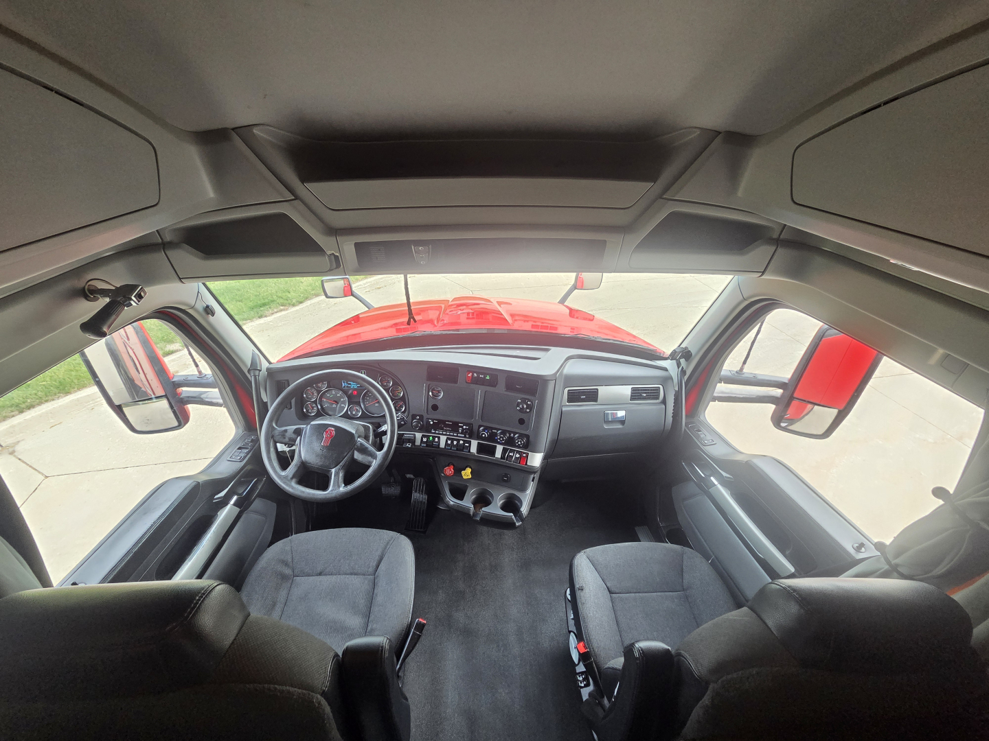 Kenworth T680 truck cabin interior from front view showing steering wheel, dashboard, and front seats.