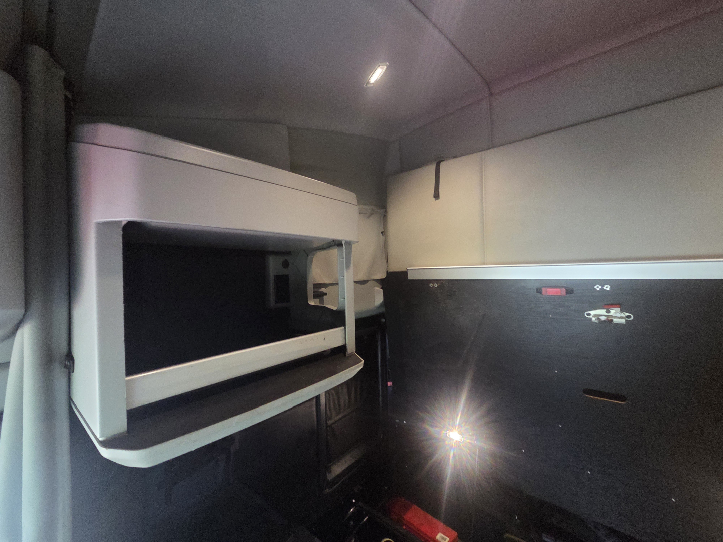 Truck cab interior showing overhead sleeper bunk and storage compartments in Kenworth T680 cabin.