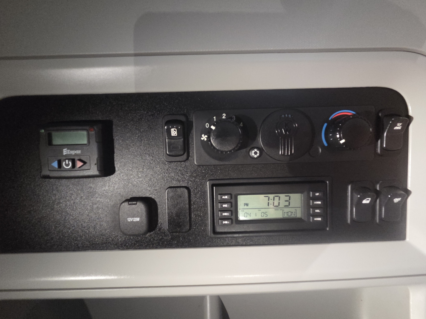Dashboard panel of a Kenworth T680 cab showing HVAC controls, digital clock, and switches.