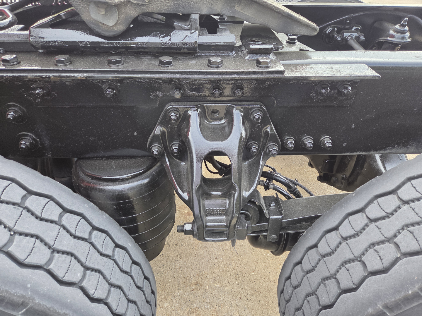 Kenworth T680 front undercarriage showing tandem axle and suspension with label text not fully legible.