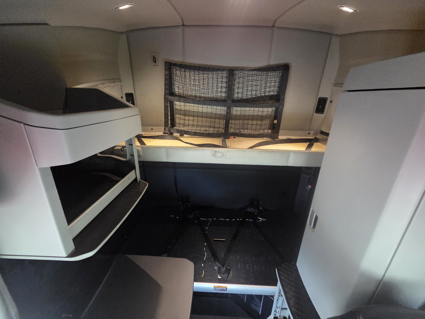 Interior sleeper cab of a 2022 Kenworth T680 showing bunks, storage compartments, and a cargo tie-down area.