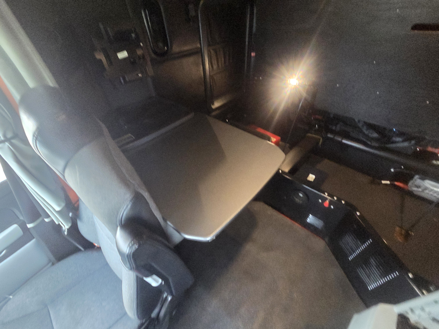 Truck cab interior of a 2022 Kenworth T680 showing a slide-out table and seating area in sleeper compartment.