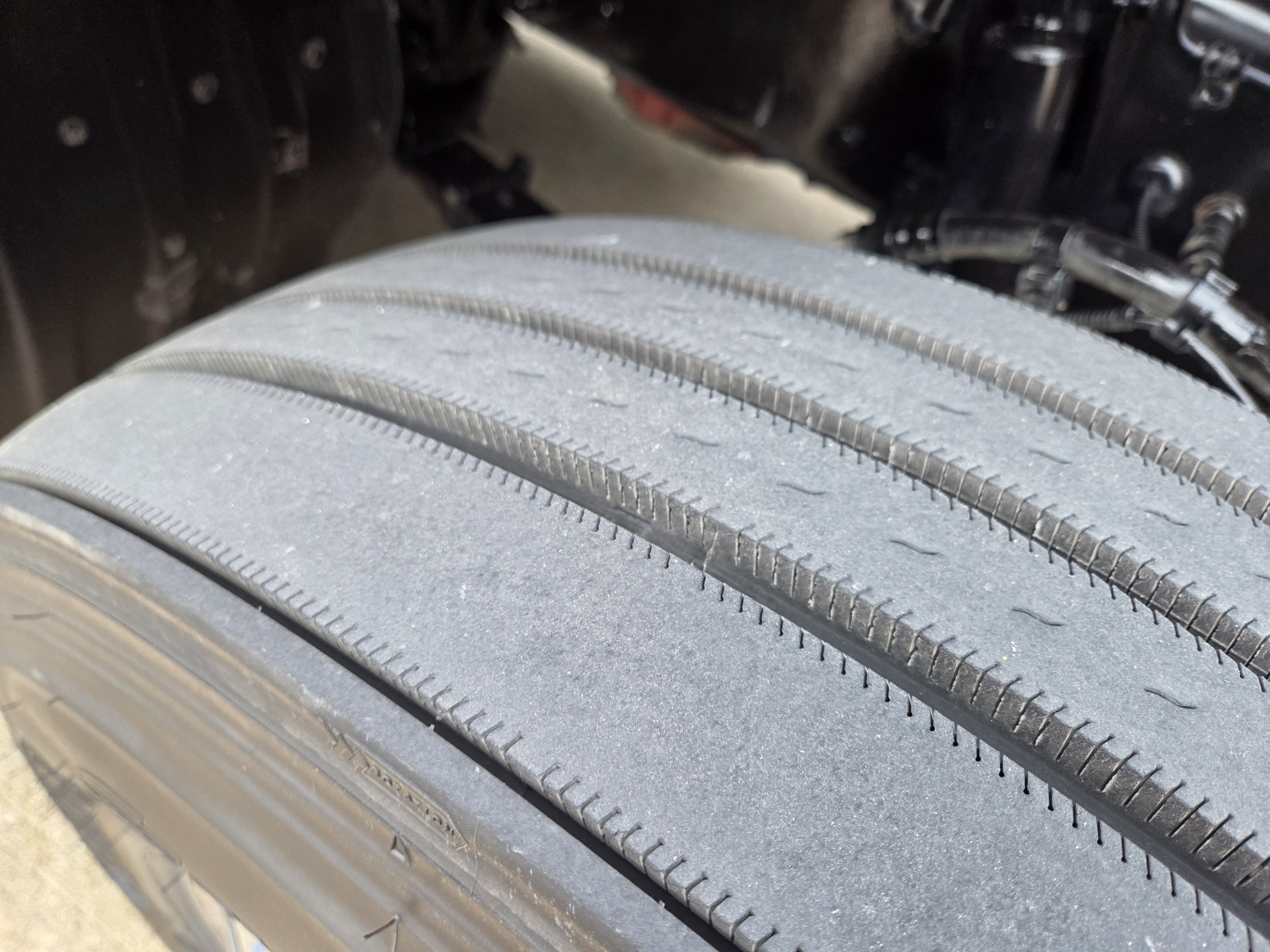 Kenworth T680 tire tread close-up in wheel well showing wear marks and tire groove detail.