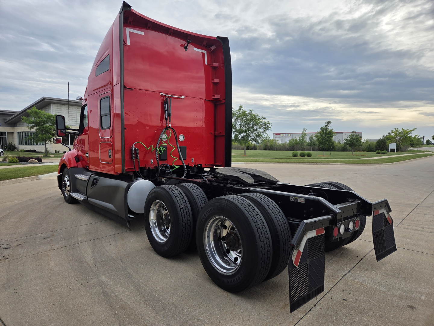 Kenworth T680 tractor cab with red exterior, rear view showing tandem axle configuration and side skirts, no visible text other than VIN/stock in listing context.