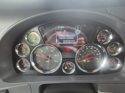 Dashboard cluster of a Kenworth T680 showing multiple gauges and a central digital display with warning about system installed, steering wheel not visible.