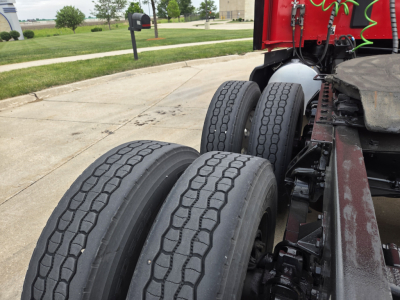 Kenworth truck rear dual axle wheels and chassis showing tire tread and nearby exhaust/air lines.