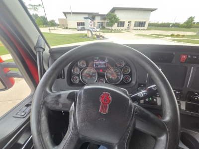 Kenworth T680 interior view showing steering wheel with Kenworth emblem and instrument cluster in dashboard.