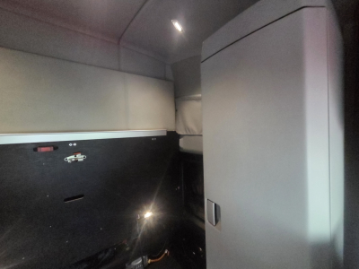 Kenworth T680 sleeper cab interior showing storage cabinet and partial wall panels.