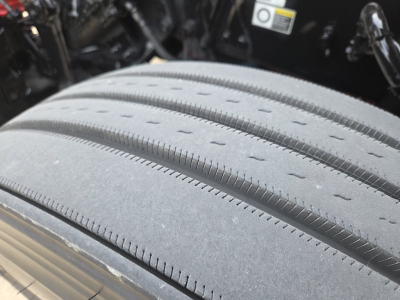 Truck wheel close-up showing treaded tire and part of engine bay in background