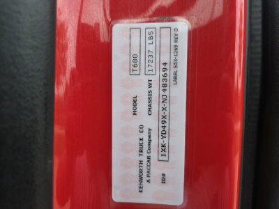 Kenworth T680 VIN sticker on door frame showing model T680, chassis weight 17237 LBS, label number 483694, and vehicle IDs; red painted surface around the label.