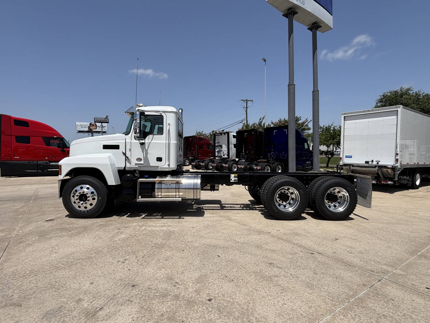 Truck chassis with cab and wheel assemblies in side view showing exposed frame and fuel tanks