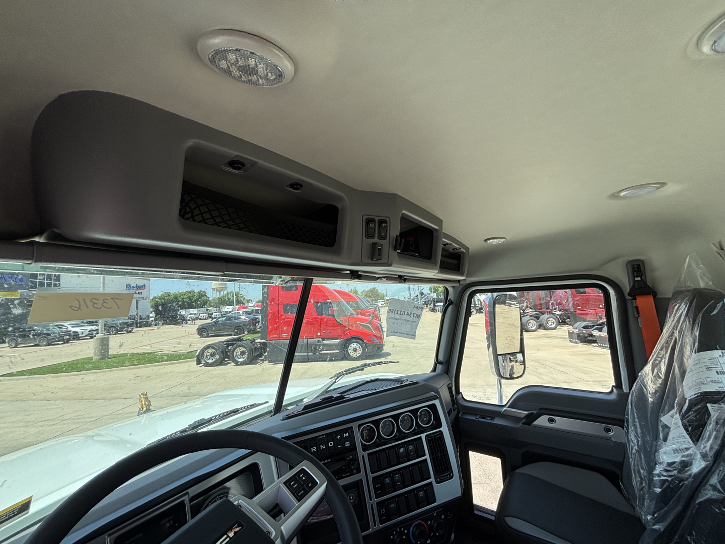 Mack PI64 truck cab interior showing dashboard, steering wheel, and overhead console.