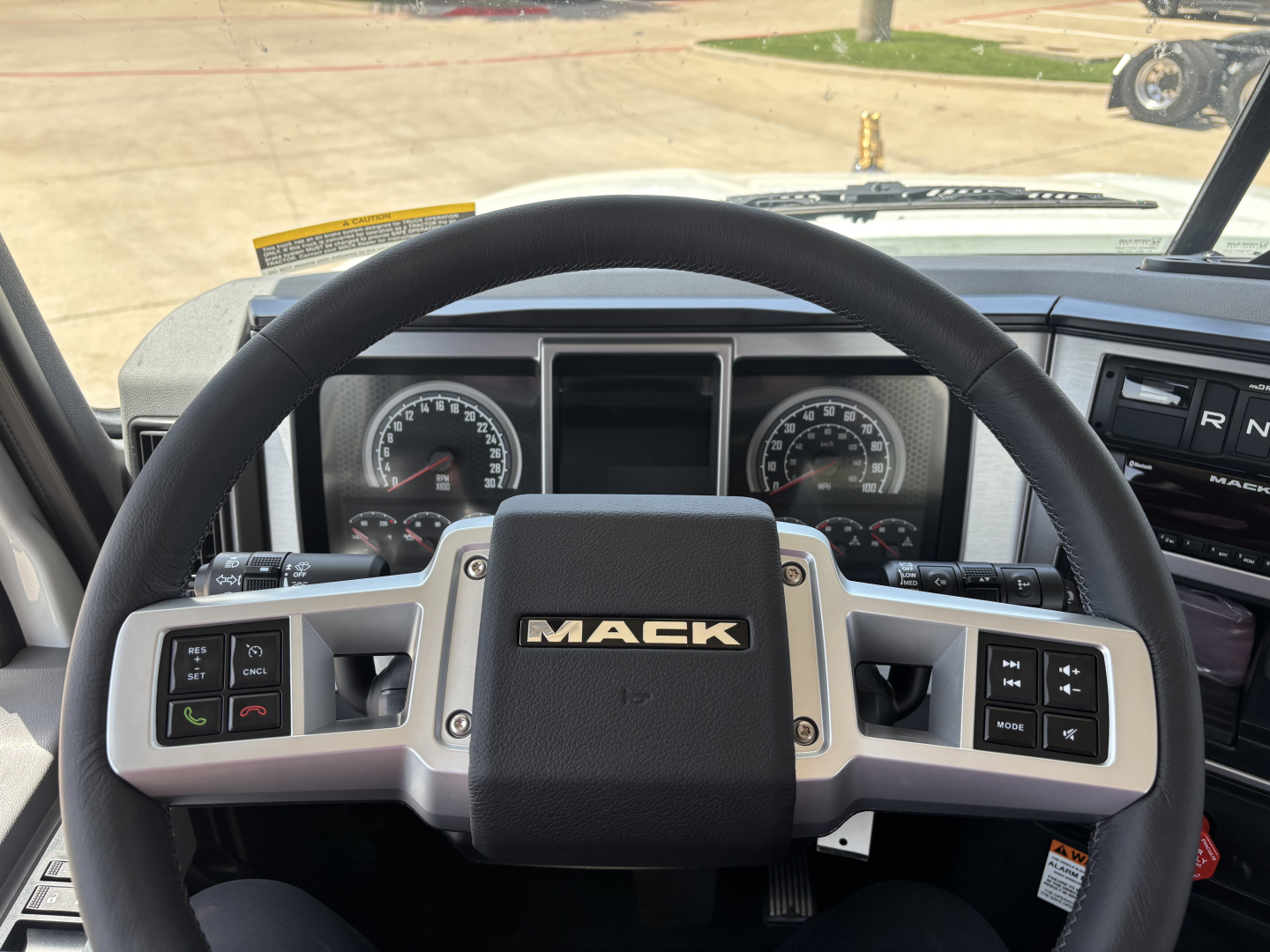 Mack PI64 truck cab interior showing steering wheel with Mack logo, instrument cluster, and control stalks.