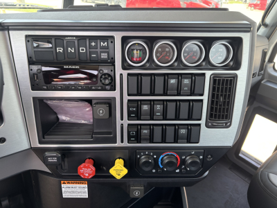 Mack PI64 dash cluster with gauges, switches, and control panel; gear selector R N D plus M; multiple gauges and climate controls visible.