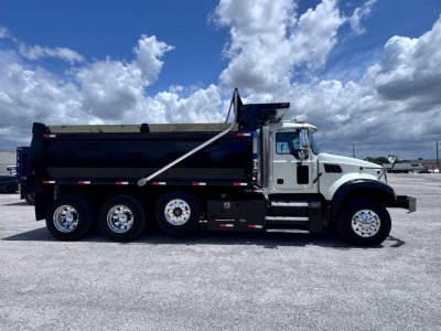 Dump truck showing Mack GR84F dump body with six wheels, black bed, white cab, side wedge, and chrome rims.