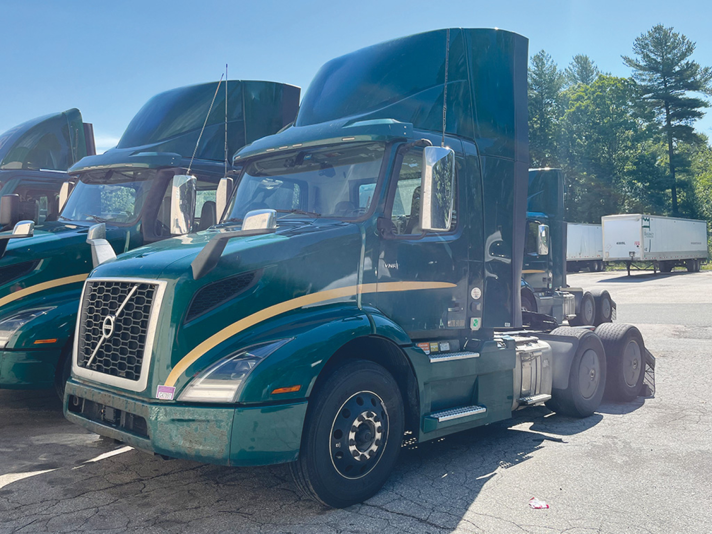 Volvo VNR 300 daycab tractor in green with tan stripe, side view showing cab and chassis.