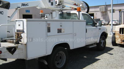 Ford F-550 service truck with boom lift side compartments and utility boxes visible in a parking lot.