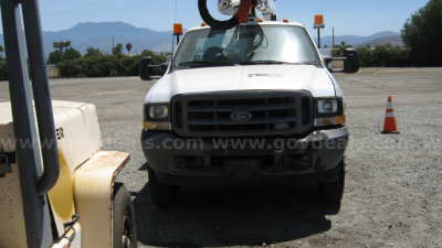 Ford F-550 work truck in a lot with boom crane equipment on top and orange cones in background.