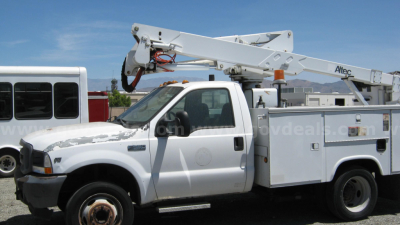 2002 Ford F-550 crew cab service truck with boom lift and Altec bucket truck body, side view showing utility compartments
