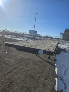 Trailer flatbed deck showing wooden planks and frame with support legs, badge plate visible on side rail.