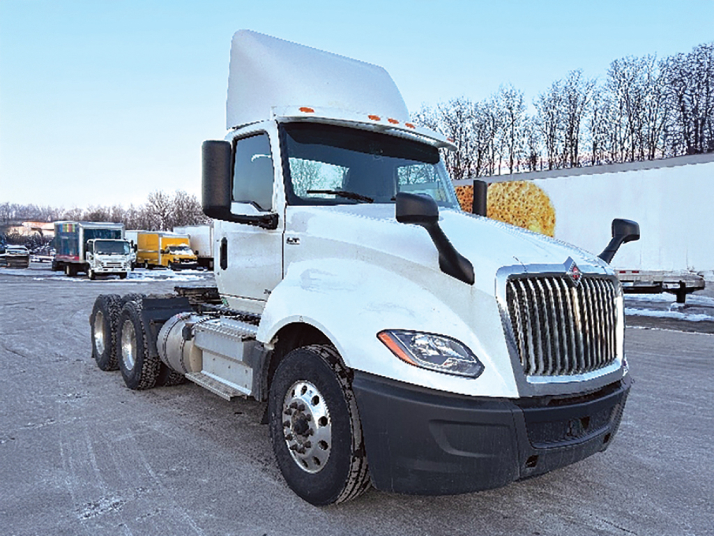Truck cab and chassis of a 2020 International LT625 daycab in a lot, front-right view showing large grille and dual rear axles.