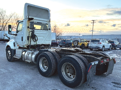 Semi truck tractor cab and chassis showing rear view with dual rear axles and fifth wheel.