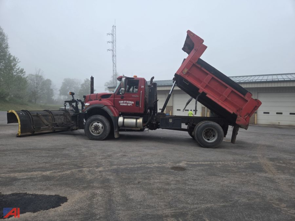 International WorkStar 7500 dump truck with raised bed, side view, red cab and dump body, logo and equipment on yard surface.