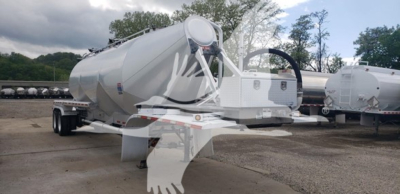 Pneumatic dry bulk trailer showing cylindrical tank on dual-axle chassis with front toolbox and hitch.