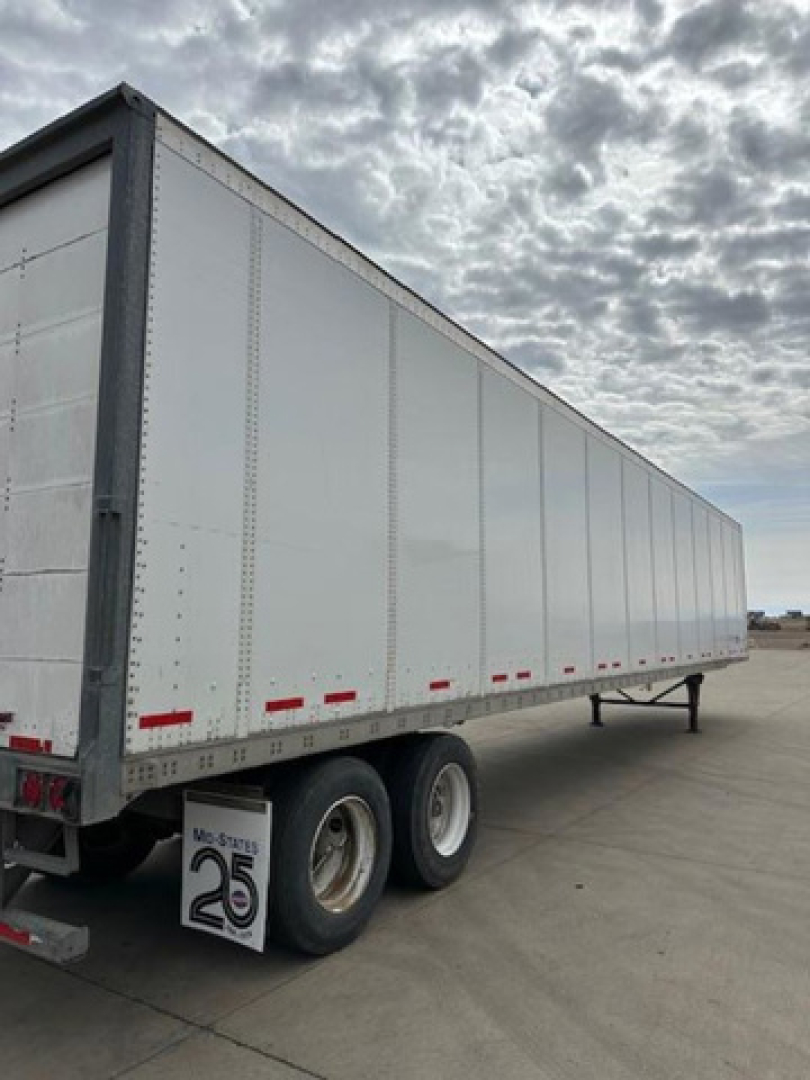 Wabash 2014 trailer van side view showing dual rear axles and white riveted panels with reflective tape and mud flaps.