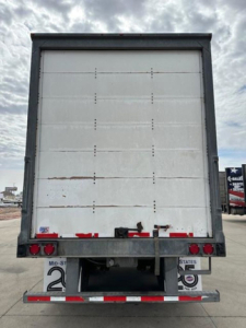 Rear view of a 2014 Wabash trailer showing a white back door with riveted panels, taillights, and rear bumper with reflective tape.