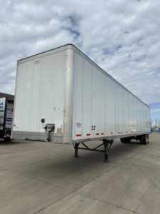 Rear view of a white Wabash trailer with raised legs and rear door, showing no visible branding in close detail.