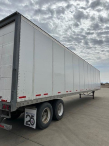 Wabash 2014 trailer van side view showing dual rear axles and white riveted panels with reflective tape and mud flaps.