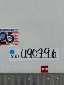 Stickered plate area with stock number label 'STK # U90796' and TFED tag on a Wabash trailer